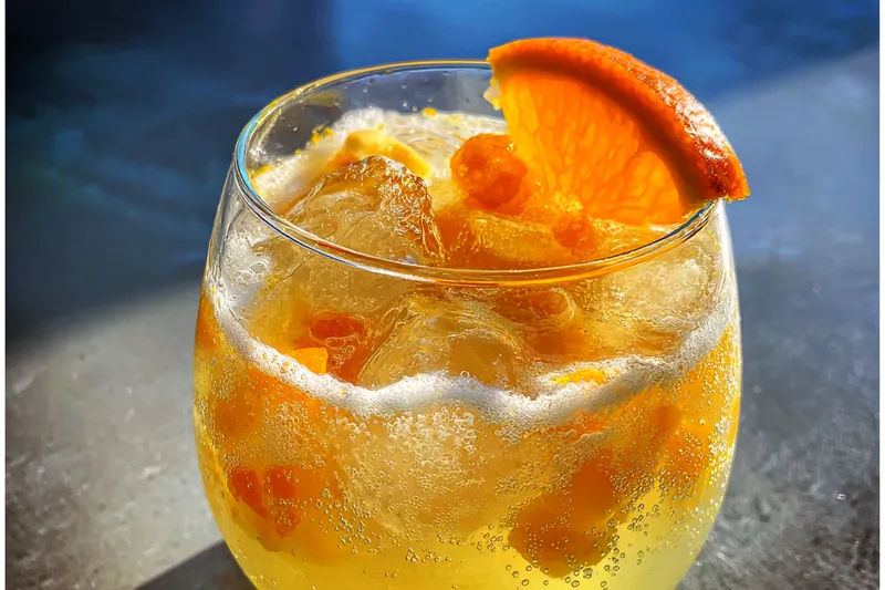 A chef mixing the Tropical Amaretto Punch Delight in a large pitcher.