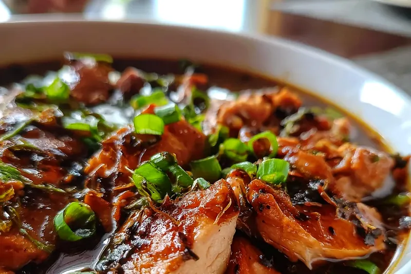 Organized ingredients including chicken thighs, bottles of dark and light soy sauce, fresh ginger root, garlic cloves, star anise, and brown sugar arranged on a wooden cutting board