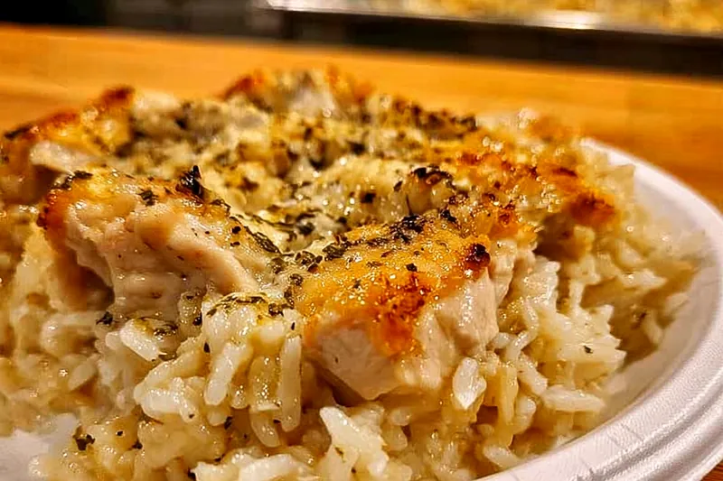 Fresh ingredients for garlic butter chicken including raw chicken pieces, butter, garlic cloves, heavy cream, herbs, and Parmesan cheese arranged on a wooden cutting board