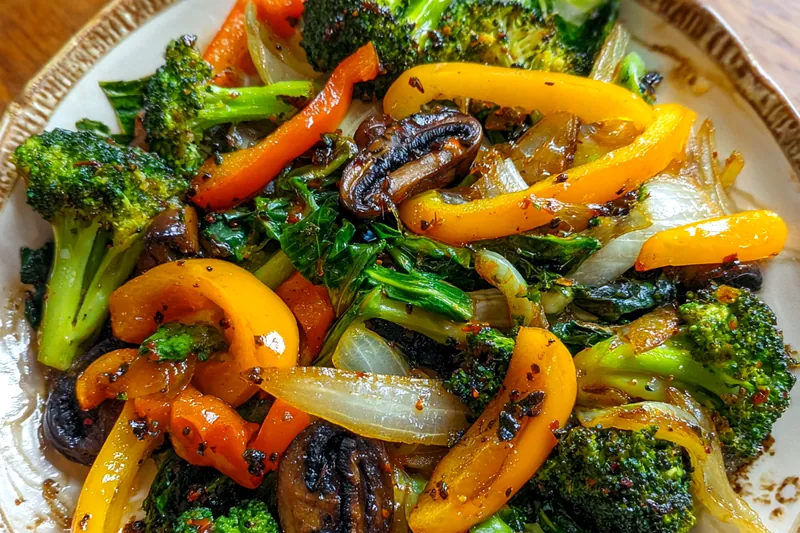 A skillet filled with colorful sautéed vegetables, sizzling in olive oil with a hint of balsamic vinegar.