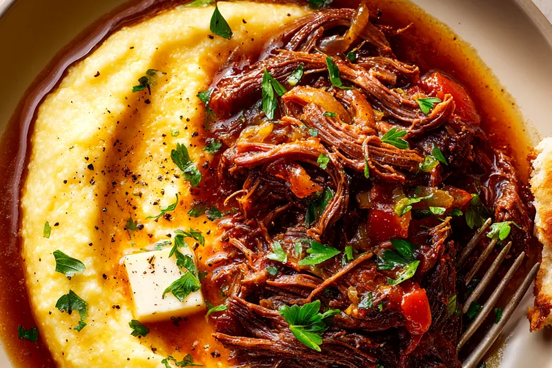 Overhead view of Italian pot roast ingredients arranged on wooden cutting board: raw chuck roast, diced carrots, celery, onions, garlic cloves, bottle of red wine, crushed tomatoes, tomato paste, fresh herbs, olive oil, and flour in white prep bowls