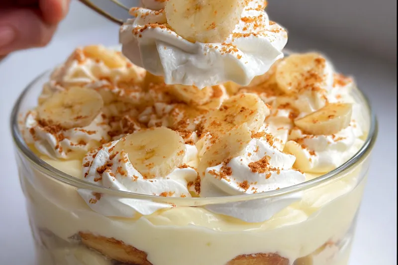 Homemade pudding base being whisked in a saucepan with steam rising, showing the cooking process for banana pudding