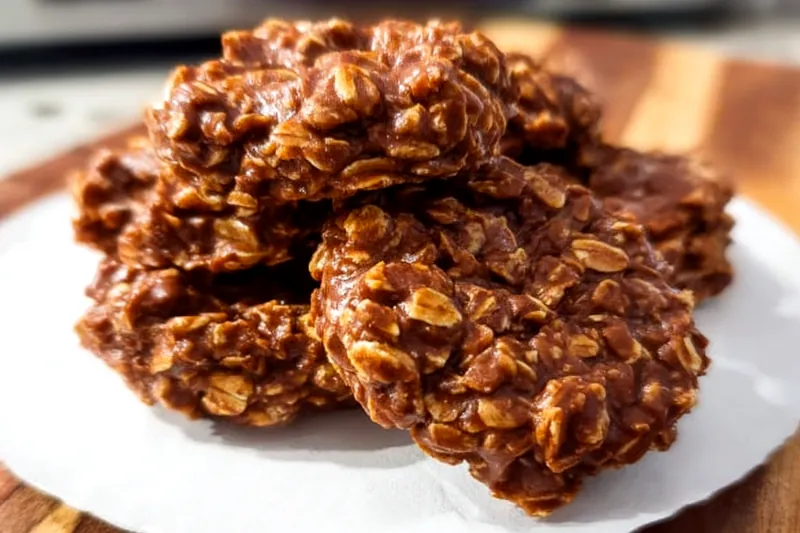 Ingredients for no-bake cookies including oats, cocoa powder, sugar, milk, butter, and peanut butter arranged on a kitchen counter