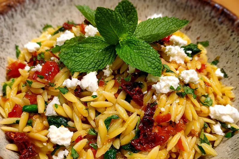A beautifully arranged display of fresh ingredients for Orzo Veggie Breakfast Bowl including bell peppers, zucchini, spinach, and orzo.